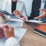 Management going over legal requirements for employee benefits in small businesses. Title: Legal Requirements for Employee Benefits in Small Businesses