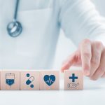Doctor moving wooden blocks with health insurance symbols